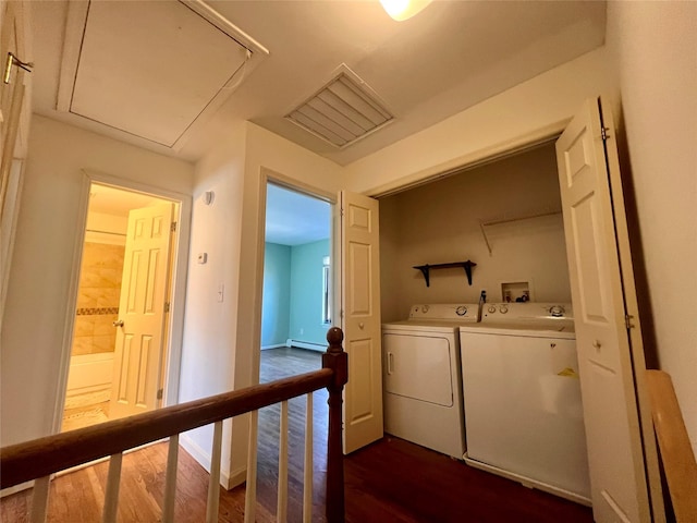 laundry area featuring a baseboard radiator, laundry area, dark wood-type flooring, washing machine and clothes dryer, and attic access