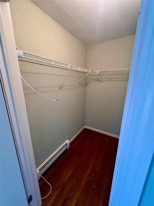 spacious closet with a baseboard heating unit and dark wood-style floors