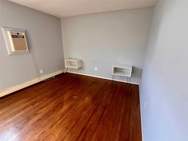 unfurnished room with baseboards, a baseboard heating unit, wood finished floors, and a wall mounted air conditioner