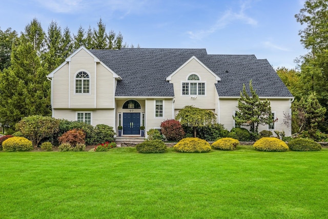 view of front of home with a front yard and roof with shingles