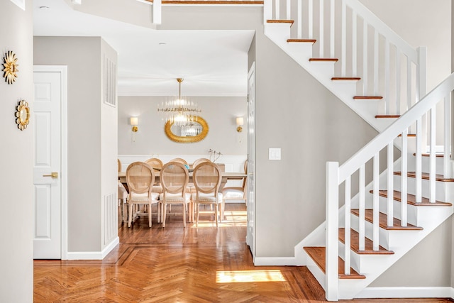 stairs with an inviting chandelier and baseboards