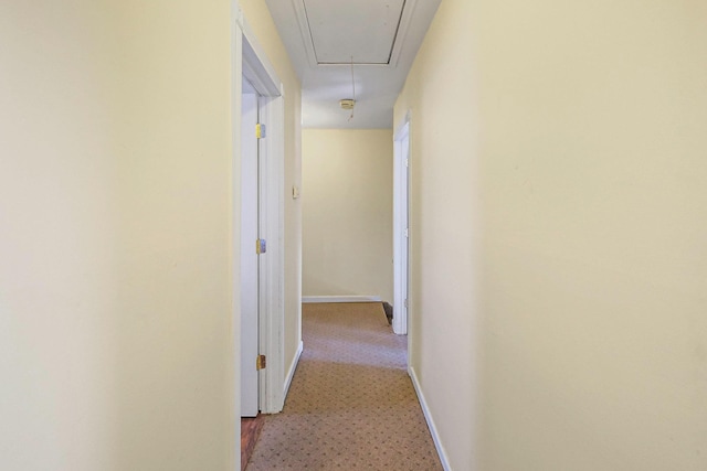 hallway with attic access and baseboards