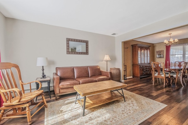 living room featuring visible vents, a notable chandelier, baseboards, and wood finished floors