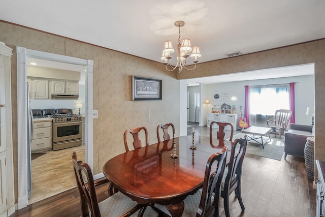 dining room with a chandelier, visible vents, and wood finished floors