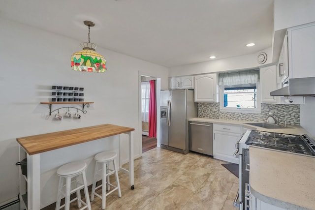 kitchen featuring white cabinetry, a baseboard heating unit, stainless steel appliances, and backsplash