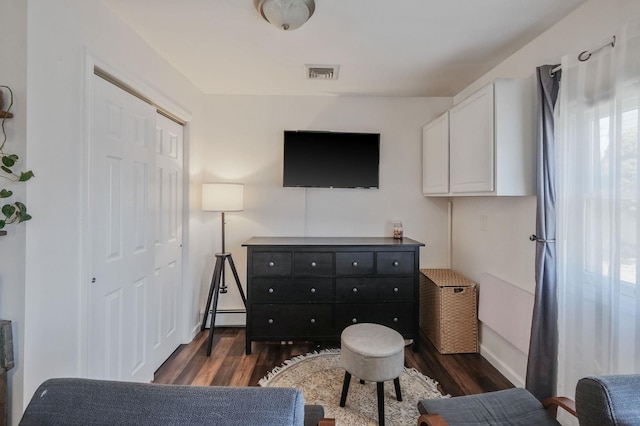 interior space with dark wood-style floors, a closet, a baseboard radiator, and visible vents