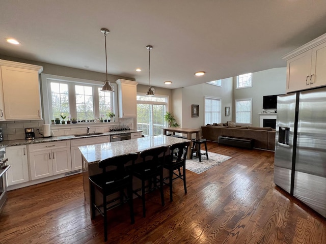 kitchen with stainless steel appliances, backsplash, a sink, and light stone countertops