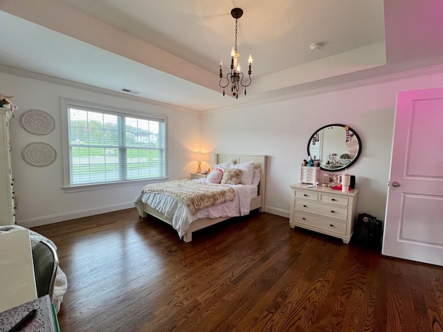 bedroom with visible vents, dark wood finished floors, baseboards, a tray ceiling, and a chandelier