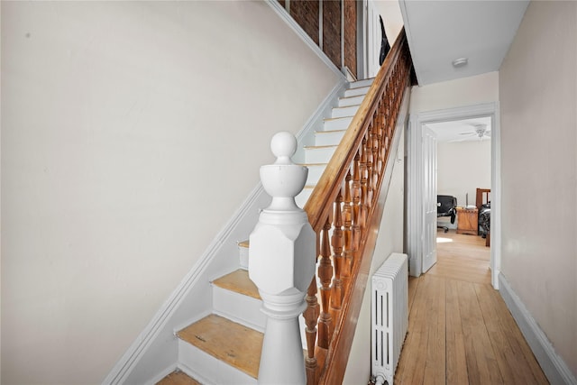 stairs featuring radiator, baseboards, and hardwood / wood-style flooring