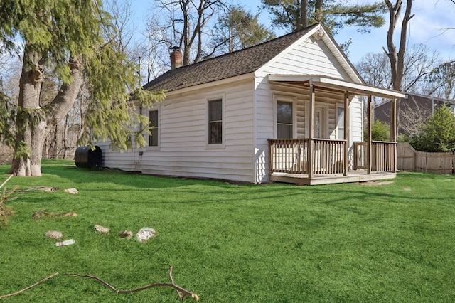 back of property featuring roof with shingles, a lawn, and a chimney