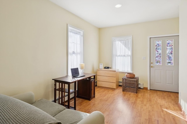 living area with light wood-type flooring, a baseboard radiator, and baseboards