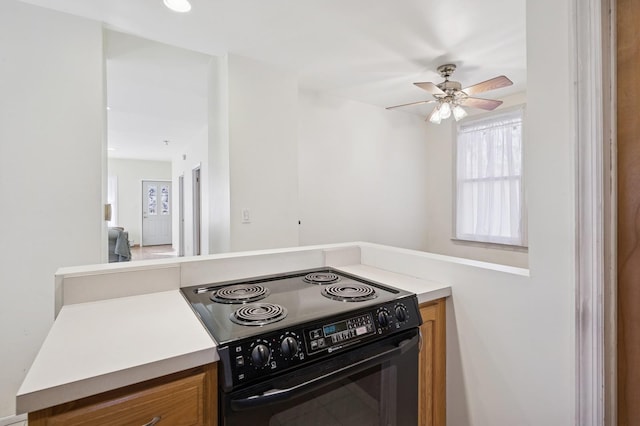 kitchen with ceiling fan, electric range, brown cabinetry, and light countertops