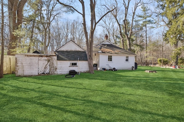 back of house featuring a chimney, fence, and a lawn