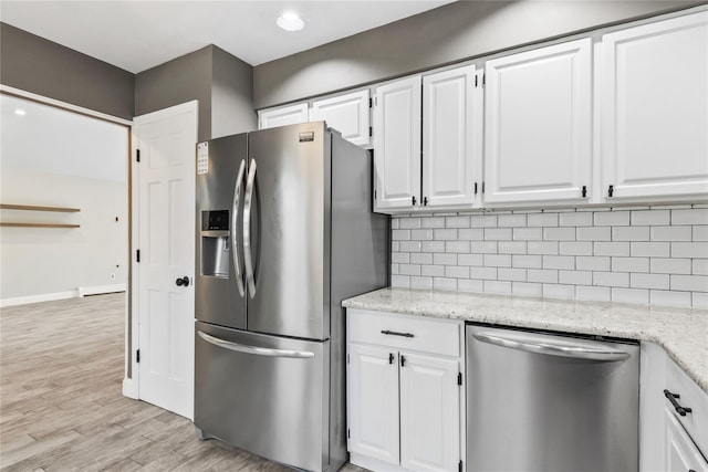 kitchen featuring stainless steel appliances, white cabinetry, light wood-style floors, and decorative backsplash