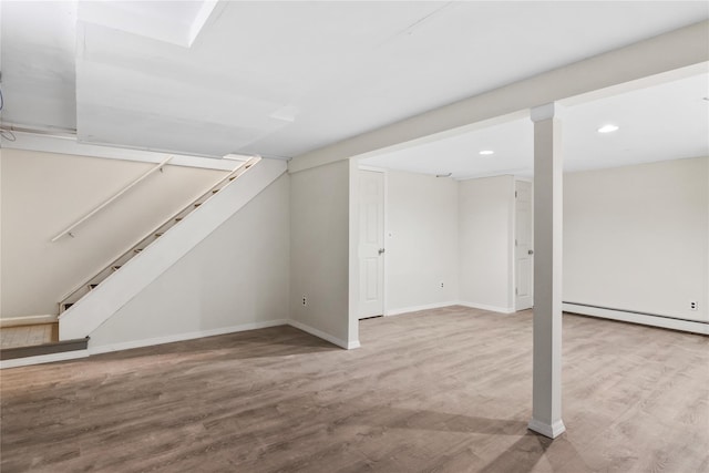 finished below grade area with a baseboard heating unit, baseboards, wood finished floors, and recessed lighting