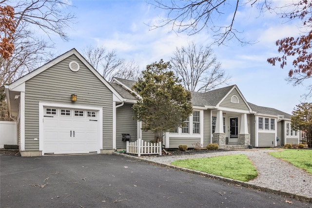 view of front of home featuring an attached garage, a shingled roof, fence, and aphalt driveway