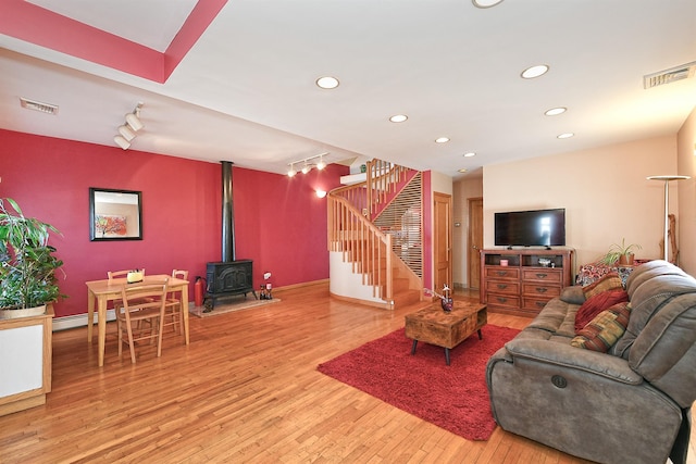 living area featuring visible vents, baseboard heating, stairway, and light wood-style flooring