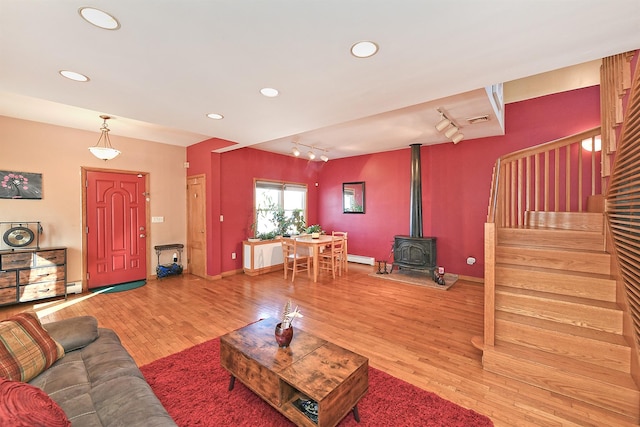 living area featuring a wood stove, stairs, visible vents, and wood finished floors