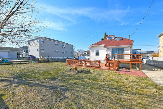 rear view of property featuring a deck, a yard, fence, and a residential view