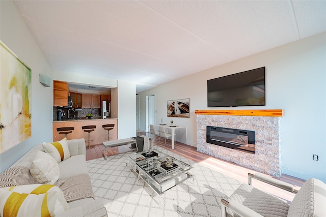 living room featuring baseboards, wood finished floors, and a glass covered fireplace