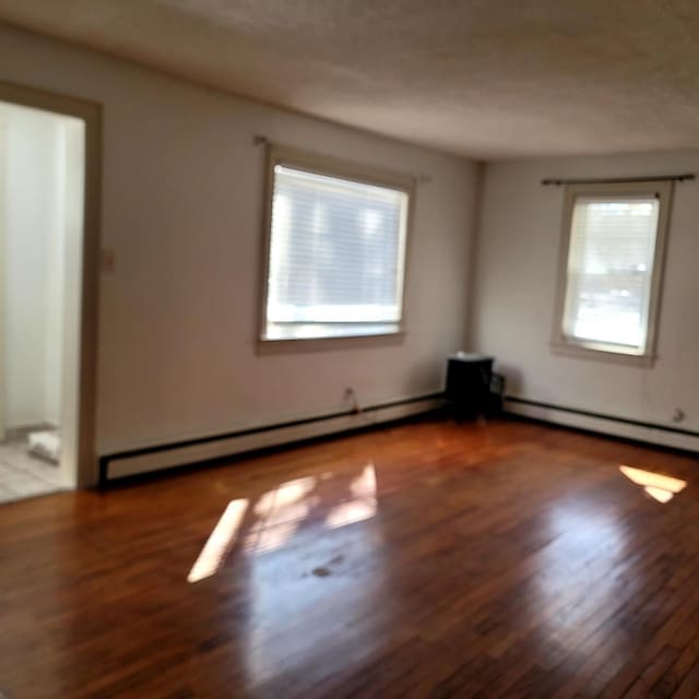 spare room featuring a baseboard heating unit, baseboard heating, and wood finished floors