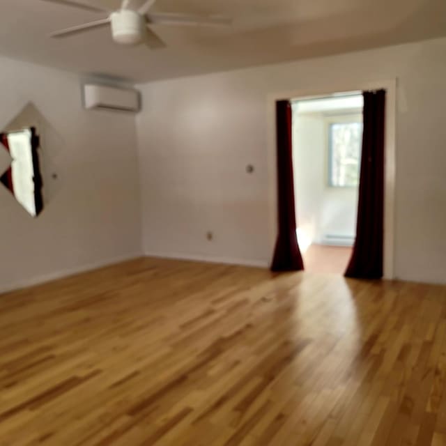 unfurnished room featuring ceiling fan, light wood finished floors, and a wall mounted air conditioner