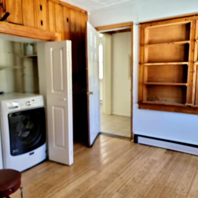 kitchen featuring washer / dryer, brown cabinets, light wood-style flooring, and baseboard heating