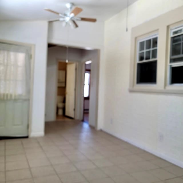 spare room featuring a ceiling fan and baseboards