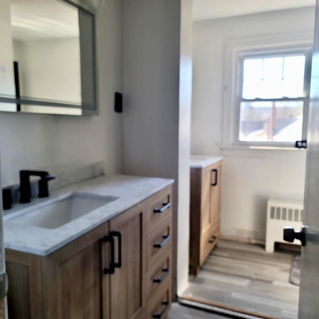 bathroom with radiator heating unit, wood finished floors, and vanity