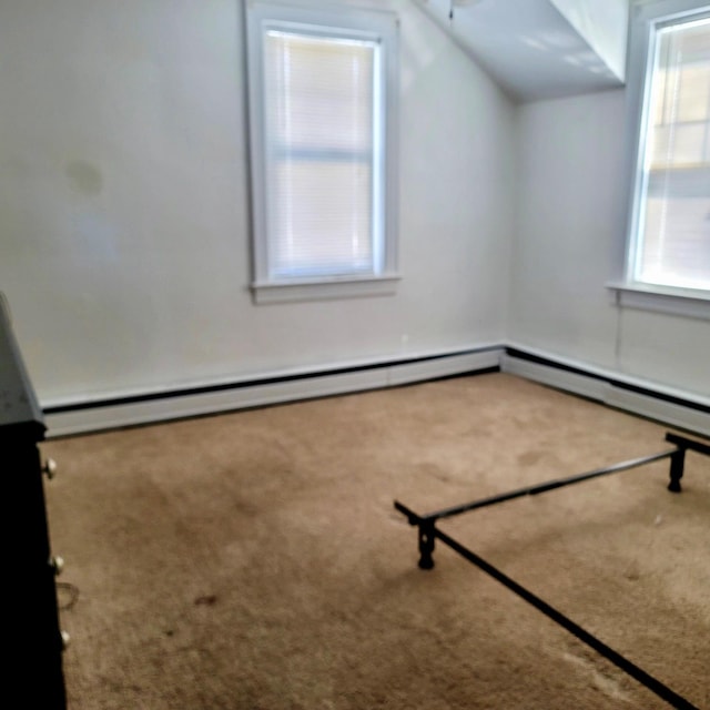 additional living space with a baseboard radiator, vaulted ceiling, and carpet flooring