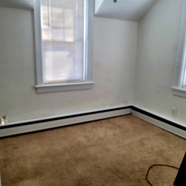 carpeted empty room featuring a healthy amount of sunlight and a baseboard radiator