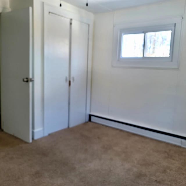 unfurnished bedroom with a baseboard radiator, a closet, and carpet flooring