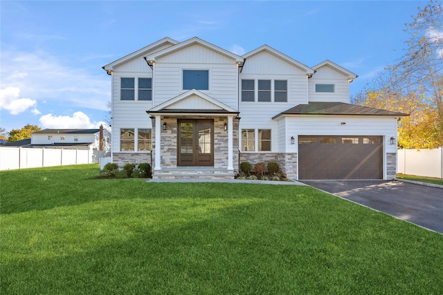 view of front of property featuring stone siding, aphalt driveway, an attached garage, fence, and a front yard