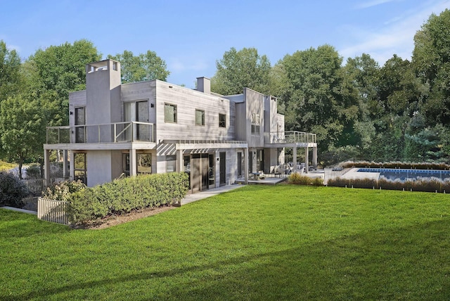 back of property with a patio, a yard, and a balcony