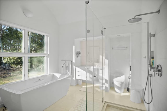 bathroom featuring toilet, vaulted ceiling, a shower stall, tile patterned flooring, and a freestanding tub