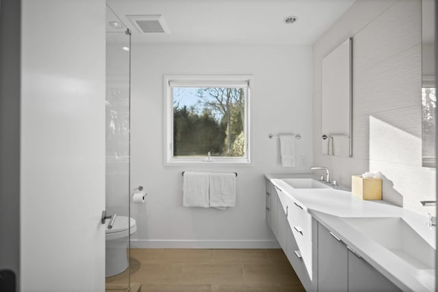 bathroom with visible vents, toilet, vanity, and baseboards