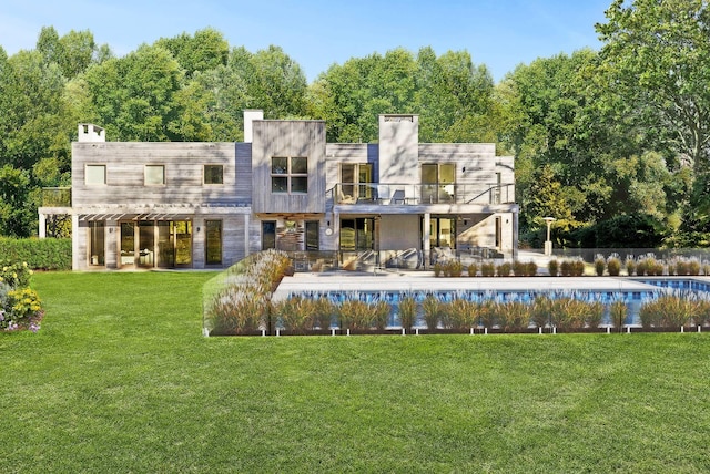 rear view of house with an outdoor pool, a patio, and a yard