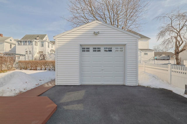 detached garage featuring aphalt driveway, fence, and a residential view