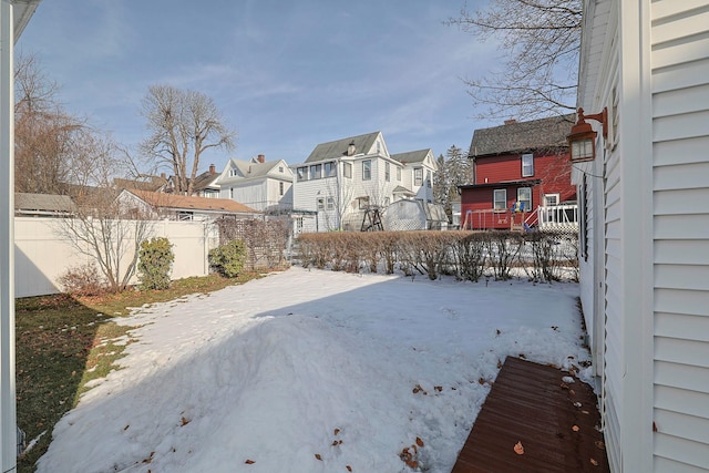 yard covered in snow featuring fence and a residential view