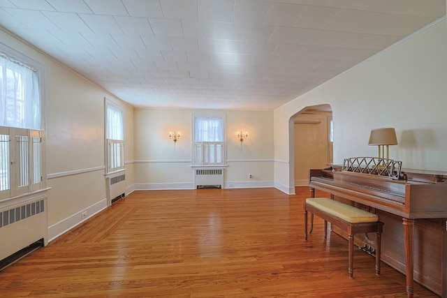 interior space featuring radiator heating unit, arched walkways, and wood finished floors