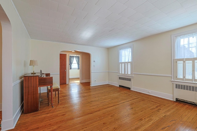 interior space featuring radiator, arched walkways, and a wealth of natural light