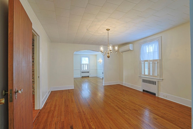 unfurnished dining area featuring radiator heating unit, a wall unit AC, and wood finished floors