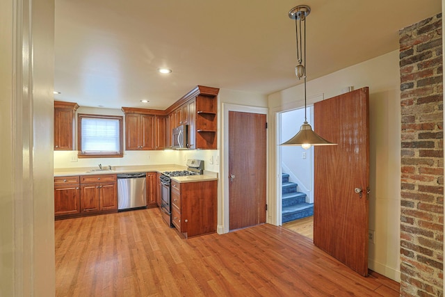 kitchen with a sink, light countertops, appliances with stainless steel finishes, open shelves, and pendant lighting