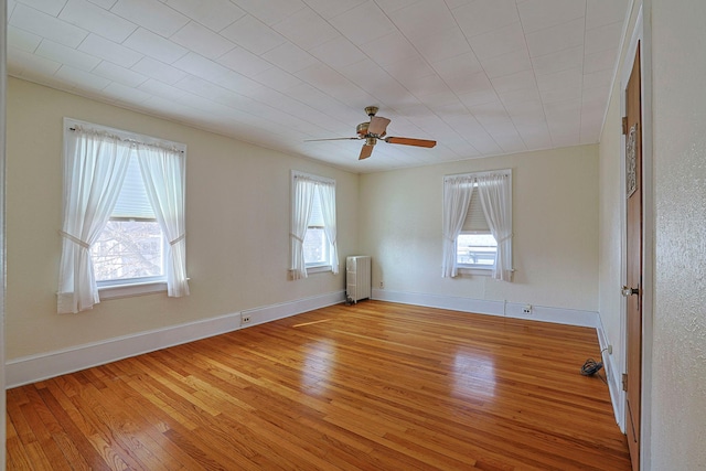 spare room featuring light wood finished floors, radiator heating unit, and plenty of natural light