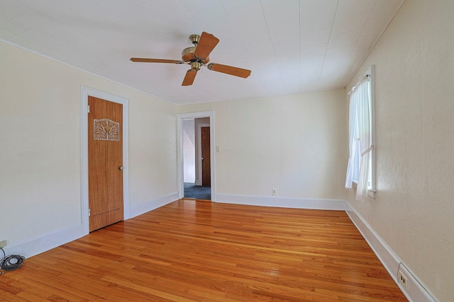 spare room featuring ceiling fan, light wood finished floors, and baseboards