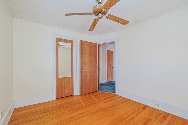 unfurnished bedroom featuring ceiling fan, ornamental molding, light wood-style flooring, and baseboards