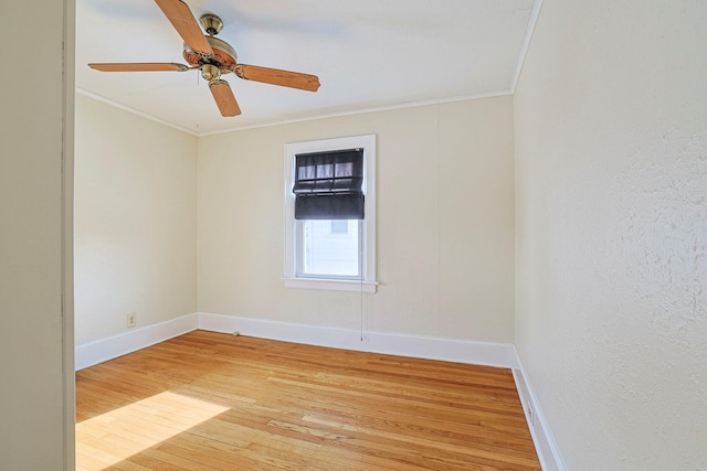 empty room with a ceiling fan, light wood-style flooring, ornamental molding, and baseboards