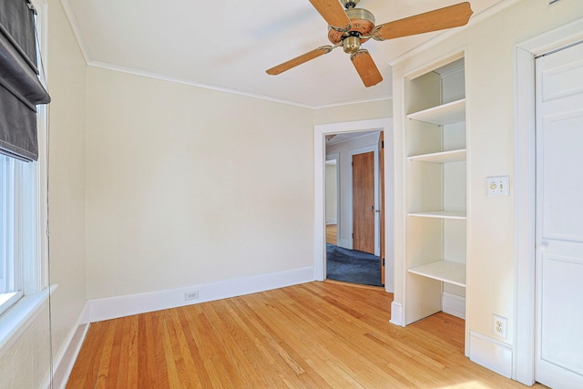 unfurnished bedroom featuring light wood-style floors, crown molding, baseboards, and a ceiling fan