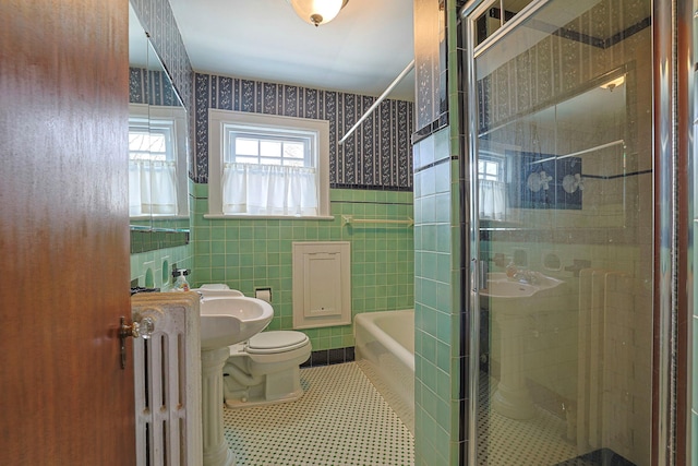 full bath featuring a washtub, tile walls, radiator, toilet, and a stall shower