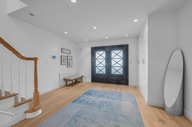 foyer entrance with stairs, light wood finished floors, and recessed lighting